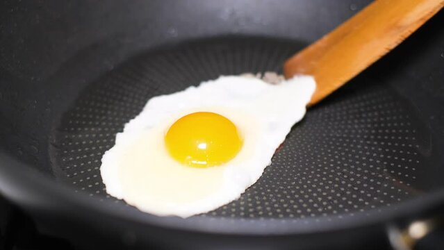 An egg is broken into a frying pan and seasoned with frying oil. Close up
