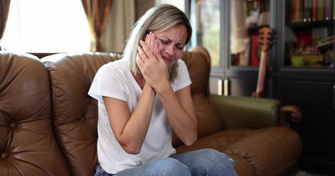 Woman with severe acute toothache at home on couch