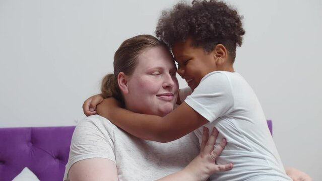Happy African-American adopted kid boy hugging foster care parent mother. Realtime