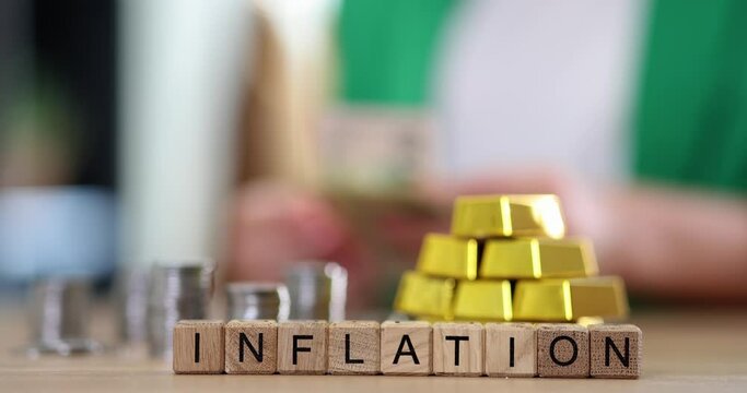 Inflation word and businesswoman counts dollars in gold bars and coins