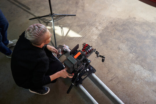 videographer sits on the floor next to a professional movie camera, sets the correct video angle