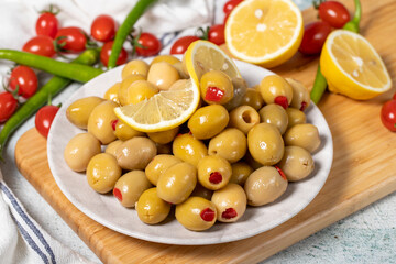 Green olives filled with red pepper. Stuffed olives on a wooden serving board. Close up