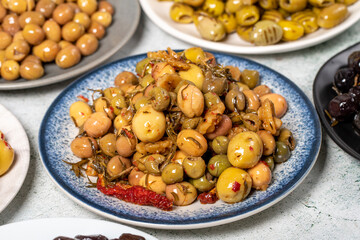 Olive varieties. Assortment of black and green olives on plate on gray background. Close up