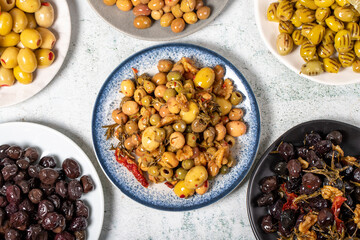 Olive varieties. Assortment of black and green olives on plate on gray background. Top view
