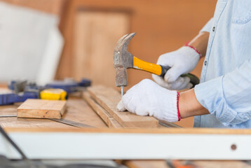Close-up of Craftsman using hammer hobnailed in workshop, Carpenter using the hammer hit a nail for assembly wood in a carpentry workshop