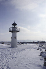 lighthouse on the coast in winter. Beautiful view on the mountains