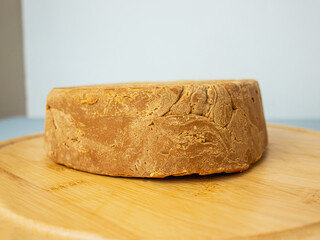 brown cheese lies on a wooden cutting board, norwegian brunost on a white background, healthy eating and nutrition, organic breakfast ingredient, traditional scandinavian brown cheese,