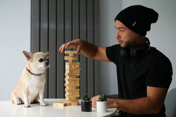 stylish teenager playing board game with his dog at home, stylish friends. Children spend interesting and useful leisure time