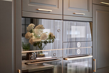 Electric oven with air ventilation. Side view of modern technology appliance against kitchen furniture.