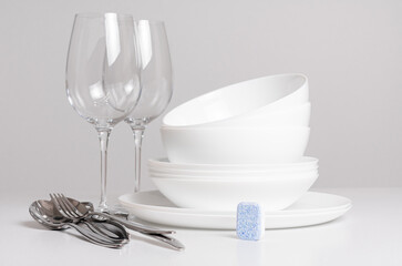 Dishwashing tablet and clean white dishes on white background