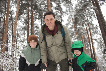 Father and sons walking in the forest with a backpack