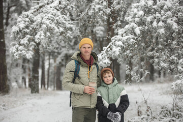 Father and son walking in the forest with a backpack