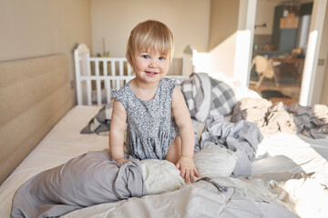 House cleaning. Happy baby girl one and half, helper are having fun and smiling while in a bright apartment. Helps parents change bed linen and do laundry in the washing machine.