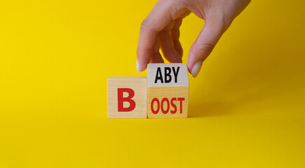 Baby boost symbol. Businessman hand Turnes cube and changes word Boost to Baby. Beautiful yellow background. Business and baby boost concept. Copy space