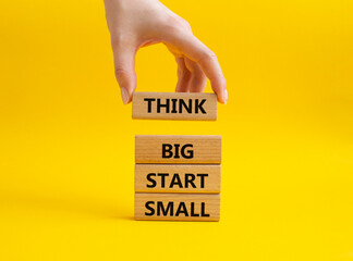 Think big start small symbol. Concept words Think big start small on wooden blocks. Beautiful yellow background. Businessman hand. Business and Think big start small concept. Copy space