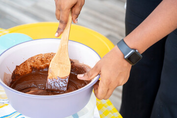 closeup of hands pouring pudding with chocolate cream on a white plate.