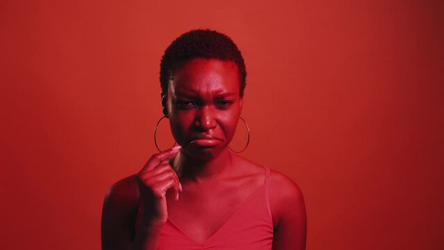 Upset grimace. Depressed mood. Offence regret. Red neon color light unhappy sad woman crying showing tear gesture isolated on dark bright gif loop boomerang animation.