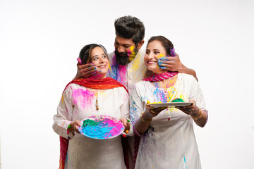 Naklejka premium Indian man applying color on women face and celebrating holi festival.