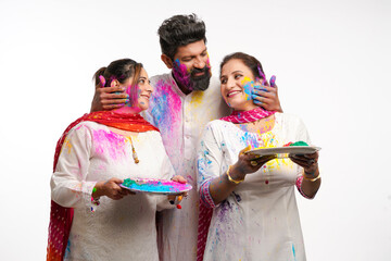 Indian man applying color on women face and celebrating holi festival.