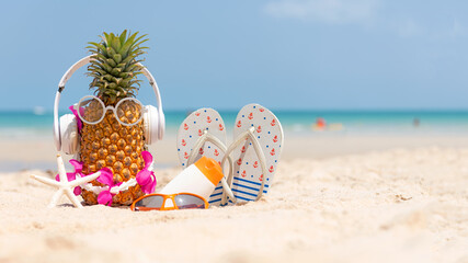 Fototapeta na wymiar Summer in the party. Hipster Pineapple Fashion in sunglass and listen music with sunblock and sandal on the sand beach beautiful blue sky background. Fashion Summer Vacation