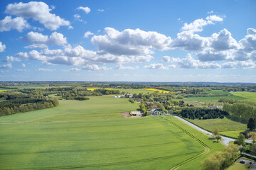 Naklejka premium Drone view of farming and agricultural fields outdoors in Europe during summer or spring. Vibrant and bright pastures growing on endless farmland with blue sky background over a vast and open meadow