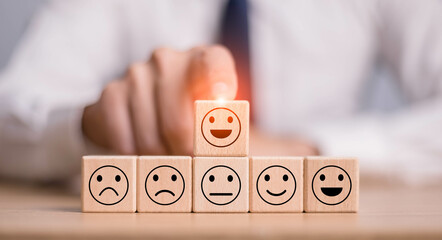 Users choose the highest satisfaction. Businessman's hand selects a smiley face on a wooden block....