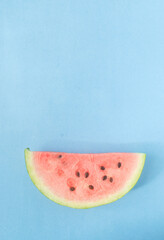Fototapeta na wymiar slice of watermelon in a blue background vertical photo 