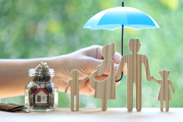 Protection,Model family with hand holding the umbrella and stack of coins money on natural green...