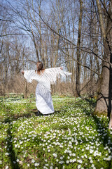 A girl in white dances in the forest on a meadow with white flowers. Person in the forest. Charming mood, tenderness, cleanliness