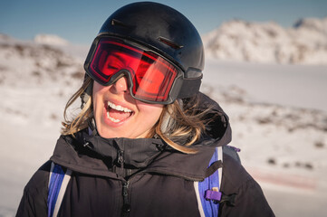 Portrait of a woman in the Alps. Smiling young woman in ski goggles and helmet stopped while skiing in ski resort