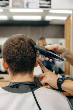 A close-up photo of a man's hair cut. A professional hairdresser cuts a man head in a barbershop. Men's beauty salon.