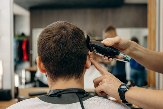 A close-up photo of a man's hair cut. A professional hairdresser cuts a man head in a barbershop. Men's beauty salon.