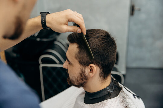 A close-up photo of a man's hair cut. A professional hairdresser cuts a man with scissors in a barbershop. Men's beauty salon.