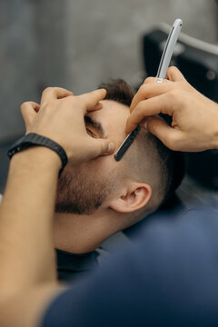 close up photo  of trimming a man's beard with a dangerous razor. A barber cuts a beard in a barbershop. Beard trimming in a beauty salon for men