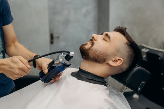 Applying hair spray to a man's beard. Haircut in a men's barbershop. Beard care.