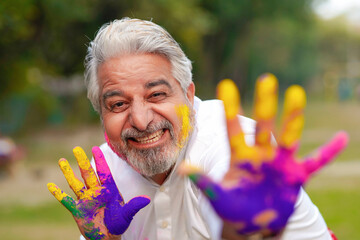 Indian man playing colors celebrating holi festival and giving expression.