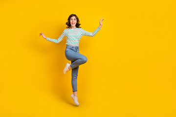 Fototapeta na wymiar Full length photo of satisfied adorable optimistic girl striped shirt denim pants flying dancing isolated on yellow color background