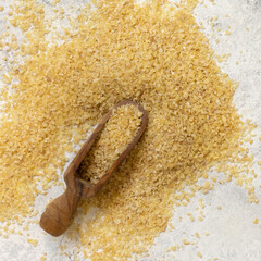 Wooden scoop of Dry uncooked bulgur wheat grain top view. Mediterranean and Middle Eastern cuisine