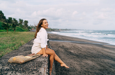 Positive woman relaxing on beach and enjoying view