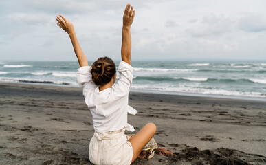 Woman raising hands up and resting on seashore
