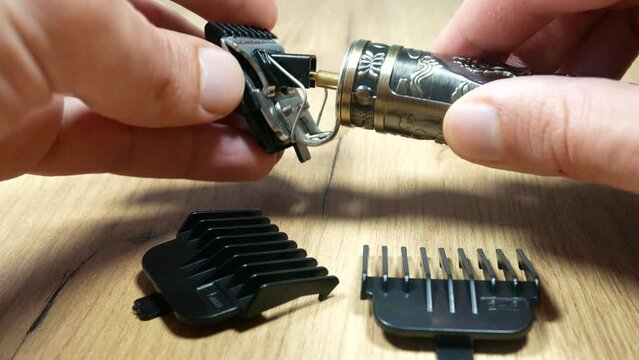 Man takes Electric metal razor or dry shaver with set of attachments for different lengths.