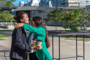 Two business colleagues hugging while meeting outdoors.