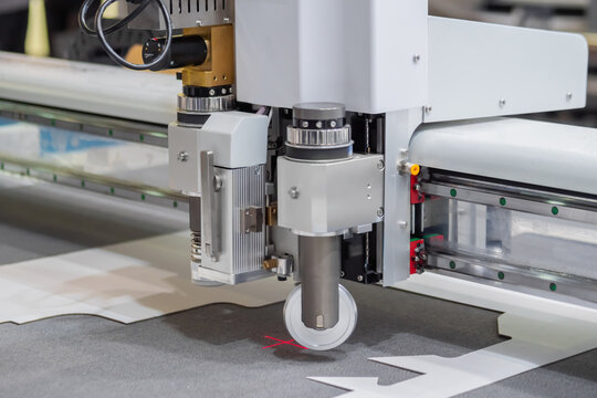 Digital flatbed cutter, plotter cutting white cardboard sheet at printer exhibition, trade show - close up. Technology, industrial, manufacturing, robotic, electronic concept