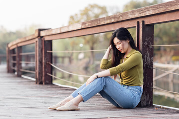 Candid lifestyle Portrait of sad young beautiful asian woman outdoor at spring. Smiling millennial girl with perfect clear glow skin and long brunette hair