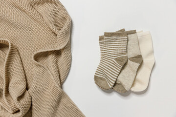Children's socks in warm colors for newborn boys or girls lie on a white background and are decorated by plaid, top view. For shops and manufacturers of children's clothing