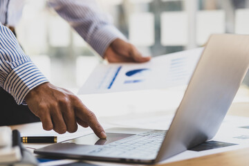 Obraz na płótnie Canvas Businessman working with laptop and analyzing financial document data for budget accounting.