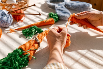 Woman making craft wool thread carrots for Easter decoration. Minimalist decor for Easter. DIY handmade craft project.