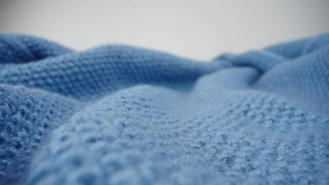 Macro dolly blue knit fabric texture, slider close-up, camera glides over knitted clothing wool textile, detailed warm pullover and sweater, textured surface. Shot with laowa probe lens