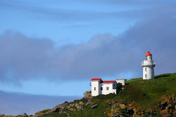 Fototapeta na wymiar The historic landmark Taiaroa Head Lighthouse at the Taiaroa Head (Pukekura), the breeding colony of the famous Royal Albatross, in blue sky background, on Otago Peninsula, near Dunedin, New Zealand