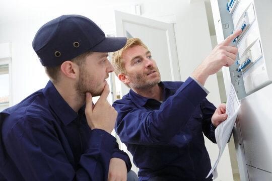 Young Male Apprentice Electrician Listening To Mentor